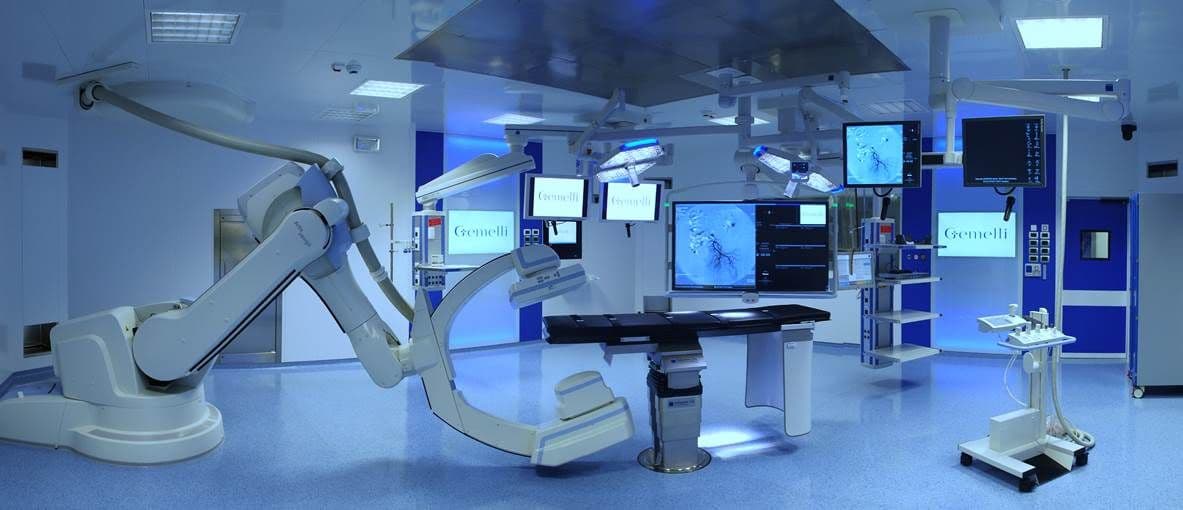 A hybrid operating theatre with a robotic imaging arm and surgical displays.