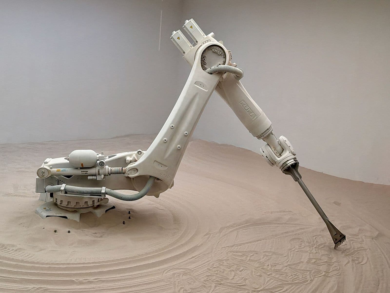 An industrial robotic arm at work in a gallery installation.