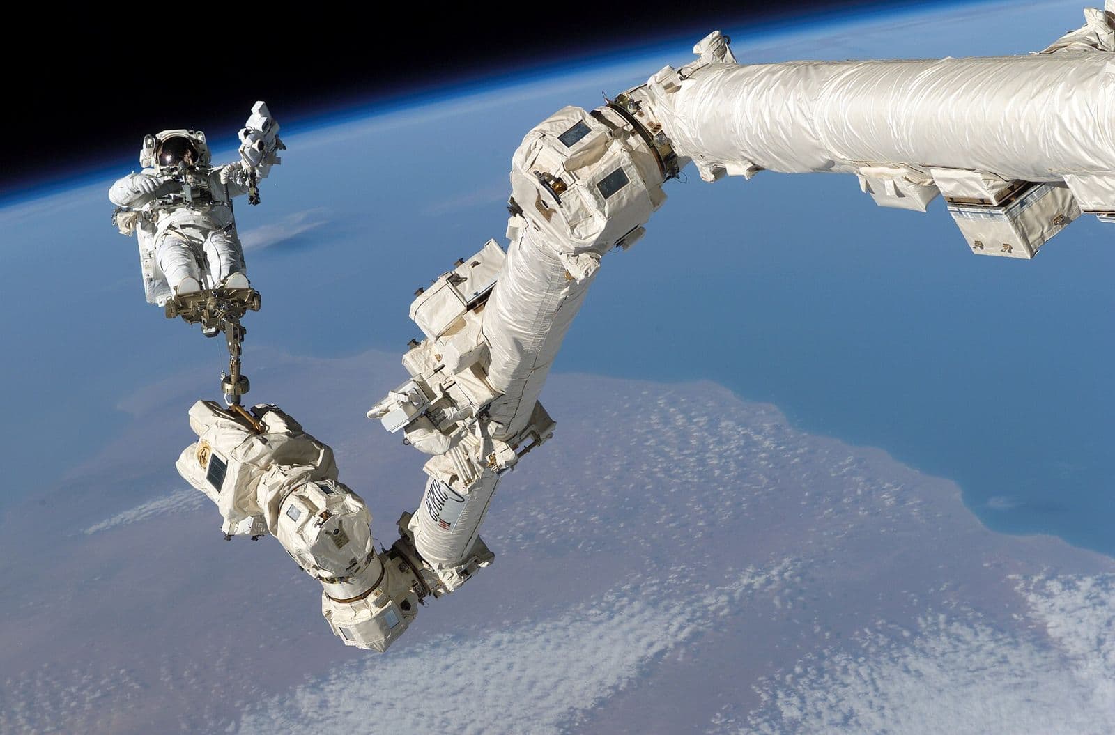A robotic manipulator arm working in orbit above the Earth.